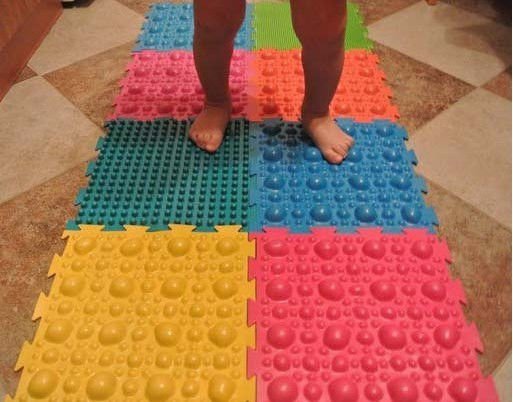 Ребенок стоит на ортопедическом коврике