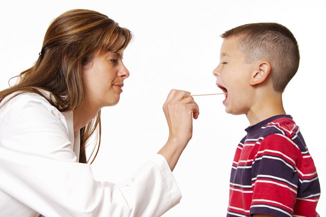 Женщина-доктор осматривает горло мальчику