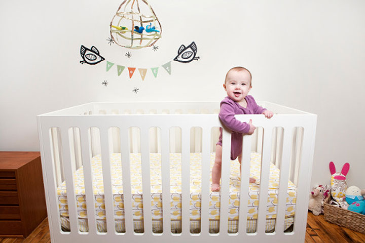 Малыш стоит в кроватке