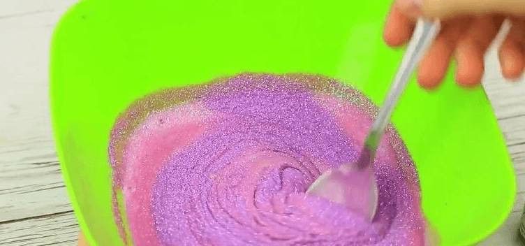 Рука мешает розово-фиолетовую смесь в тарелке