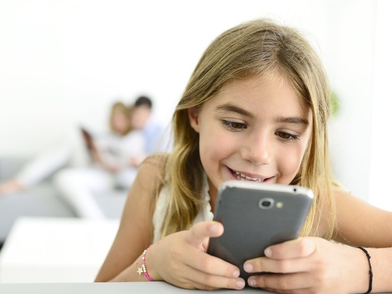 Девочка увлечённо смотрит в смартфон