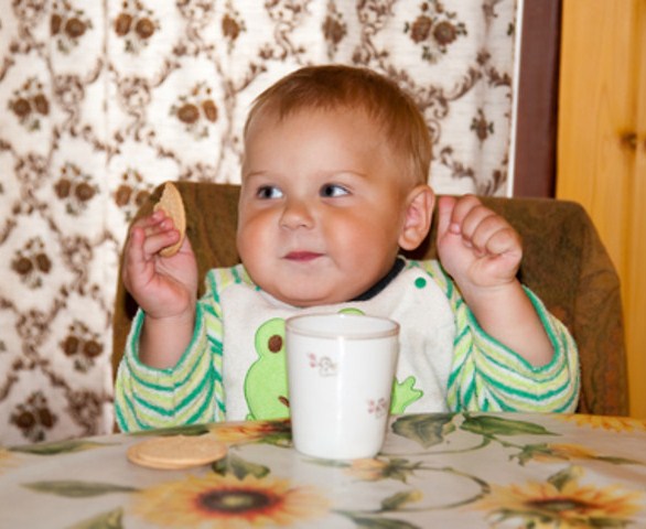 Годовалый малыш ест печень, рядом стоит кружка