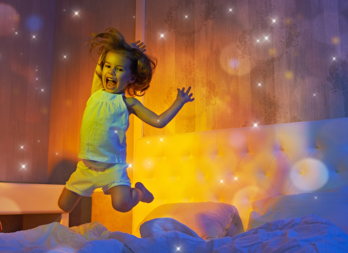 Девочка вечером прыгает по кровати