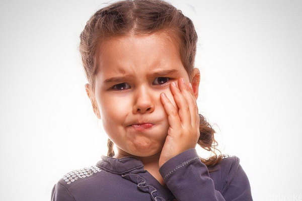 Девочка держится за щёку — у неё болит зуб