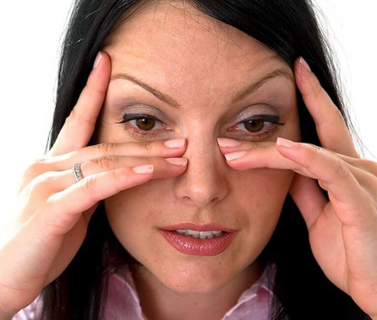 женщина приложила пальцы к боковым поверхностям носа