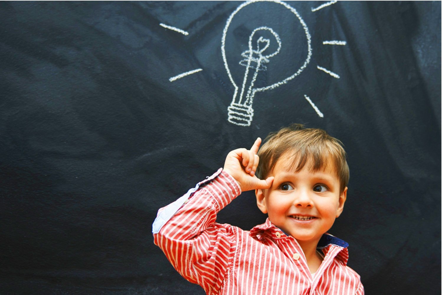 На доске мелом изображена светящаяся лампочка; мальчик о чём-то думает и держит вверх указательный палец