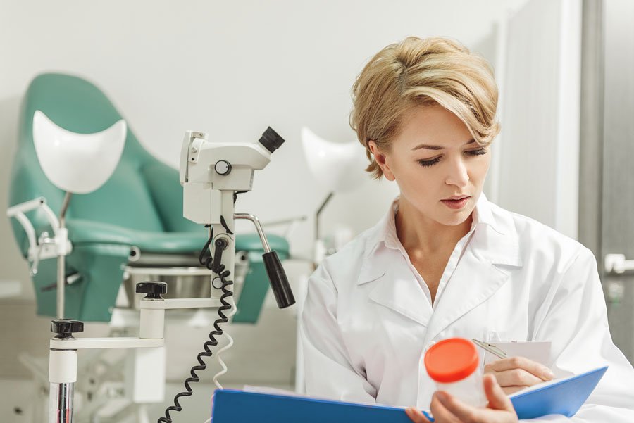 Гинеколог (женщина) в своём кабинете изучает документ