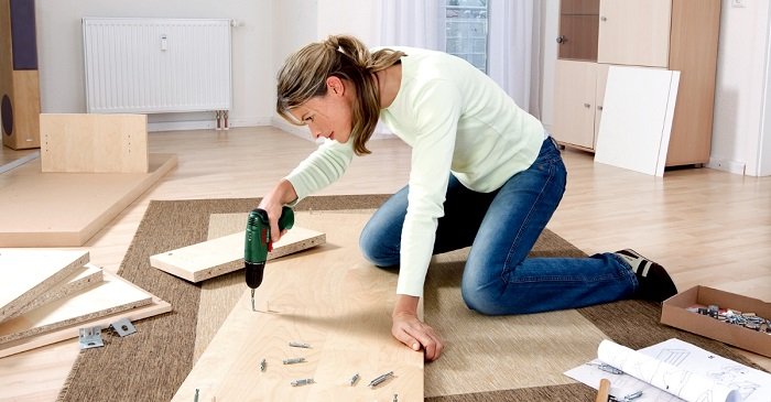 Женщина сама собирает мебель дома