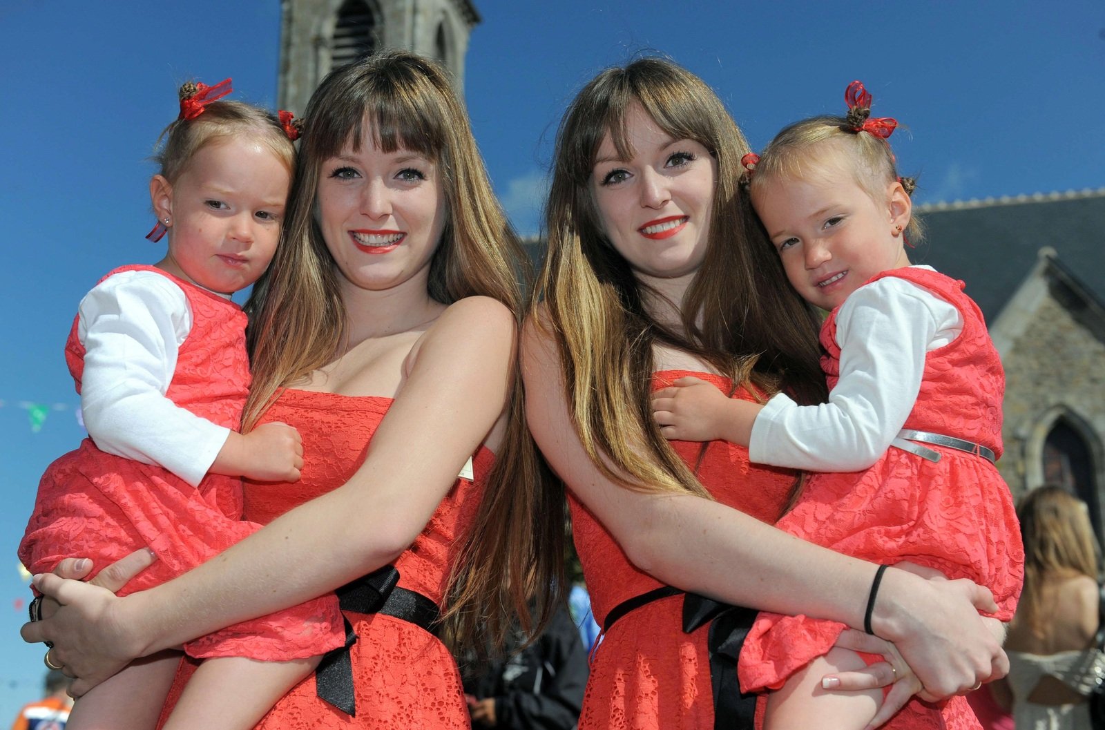 Сёстры-близнецы держат на руках маленьких близняшек