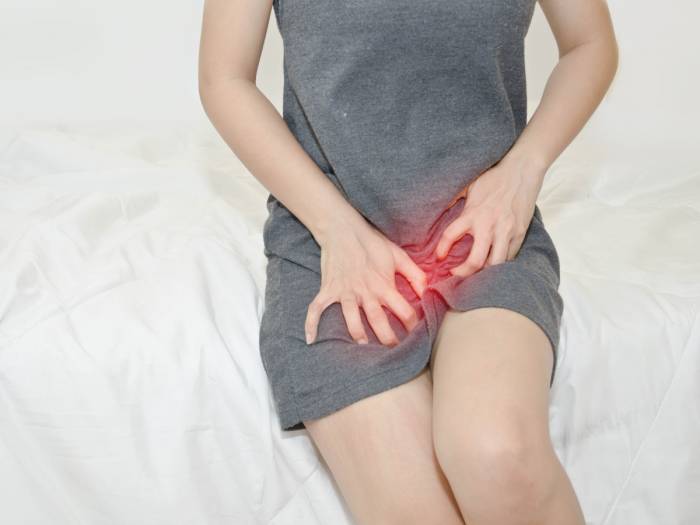 У женщины область влагалища подсвечивается красным на фоне серого платья