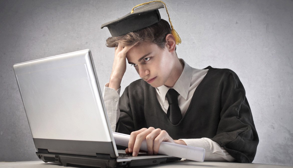Парень-выпускник сидит за ноутбуком