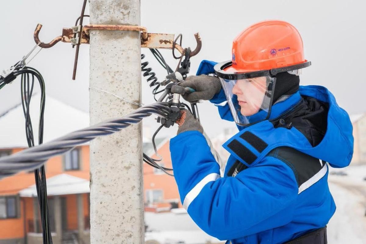 Электромонтёр крепит провода на столбе