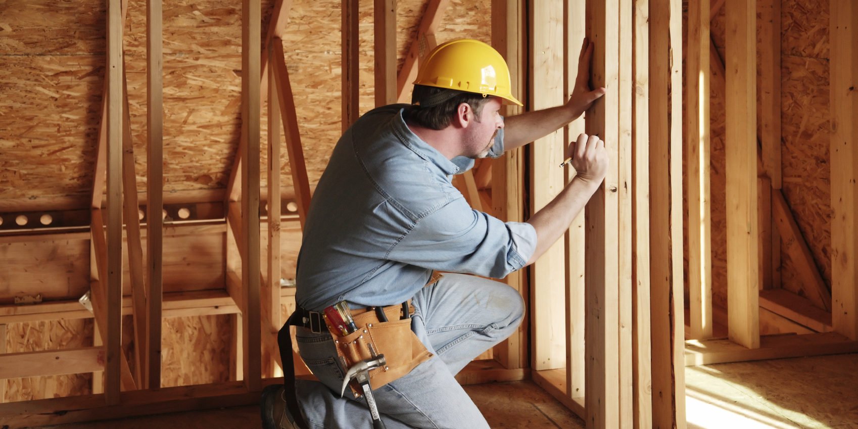 Плотник делает разметки при работе с деревом