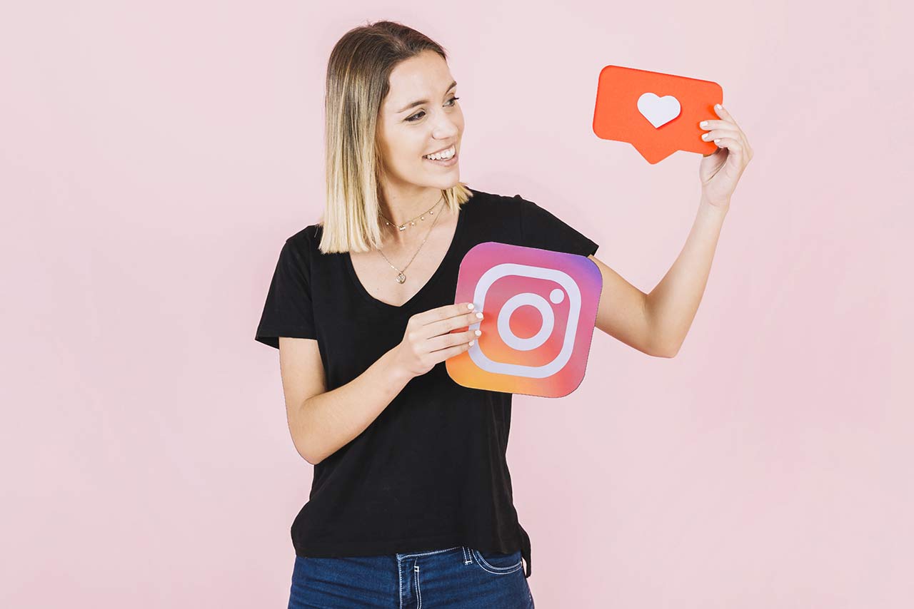 Девушка держит в руках таблички с логотипом Инстаграма и лайком