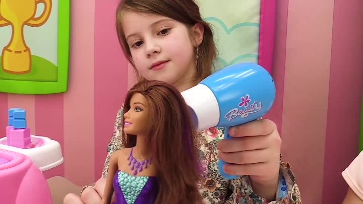 Девочка сушит феном волосы кукле Барби