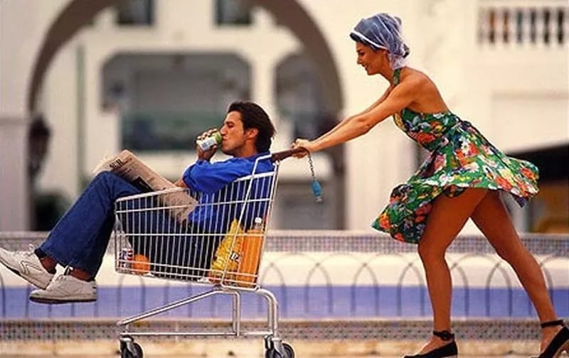 Женщина везёт в мужчину в продуктовой коляске