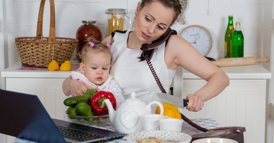 Мама держит на руках ребёнка, одновременно разговаривает по телефону, смотрит в ноутбук и режет лимон