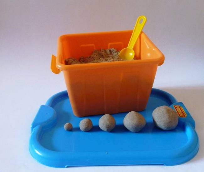 Шарики из кинетического песка рядом с контейнером