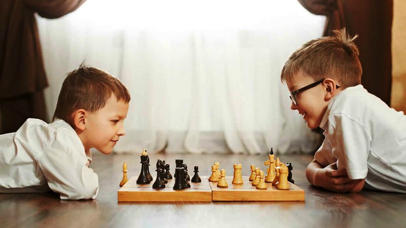 Два мальчика играют в шахматы, лёжа на полу