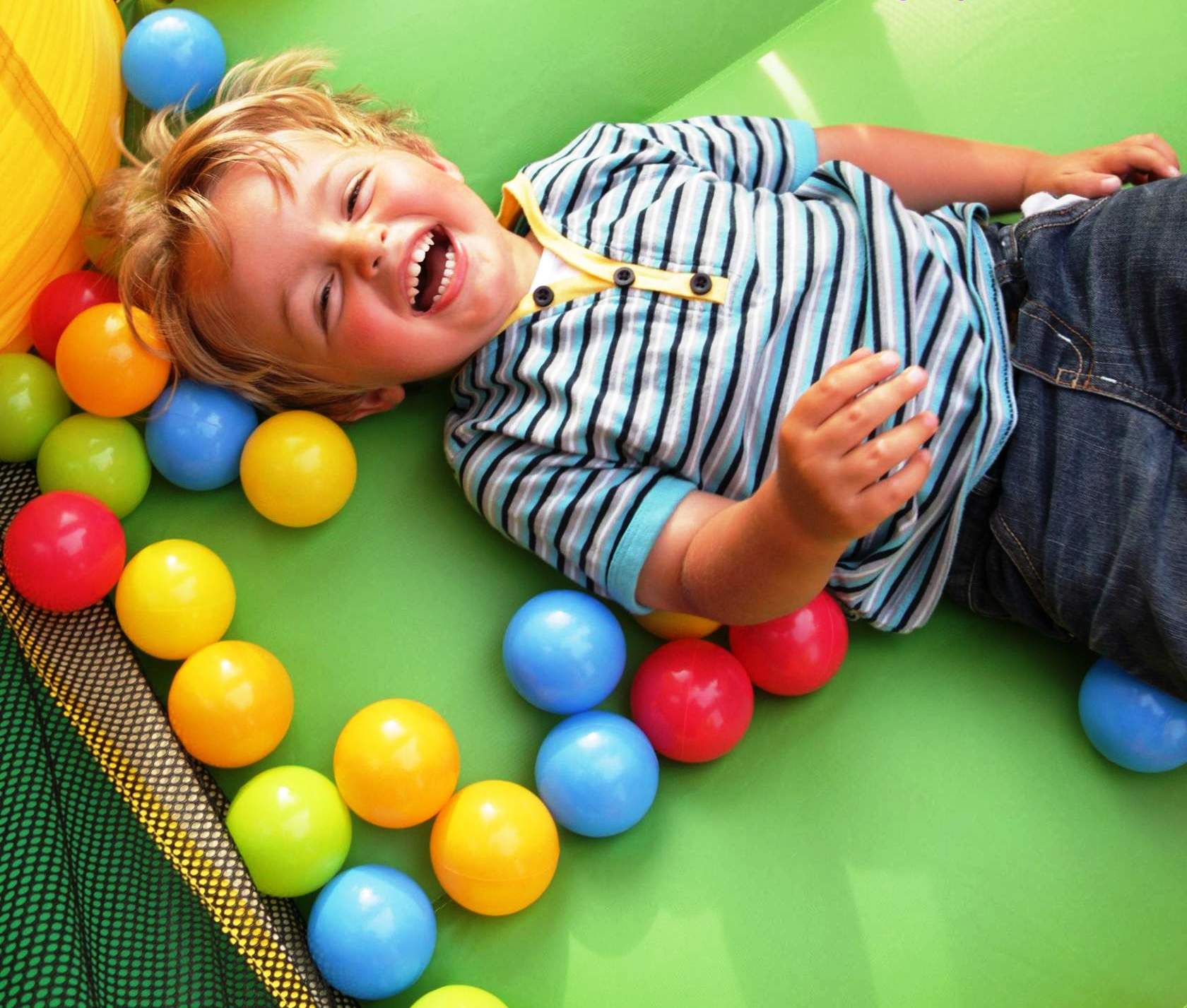 Мальчик лежит в шариках сухого бассейна