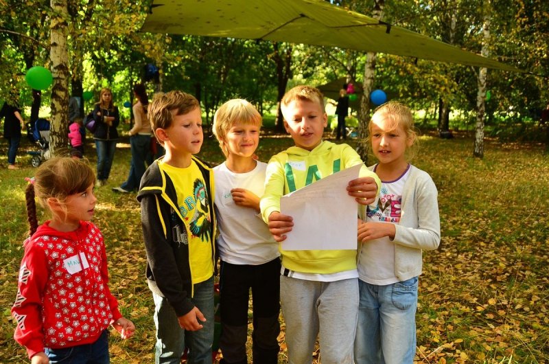 Дети в парке читают текст на листе бумаги