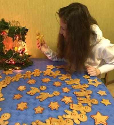 Имбирные пряники на столе, на стуле сидит девочка