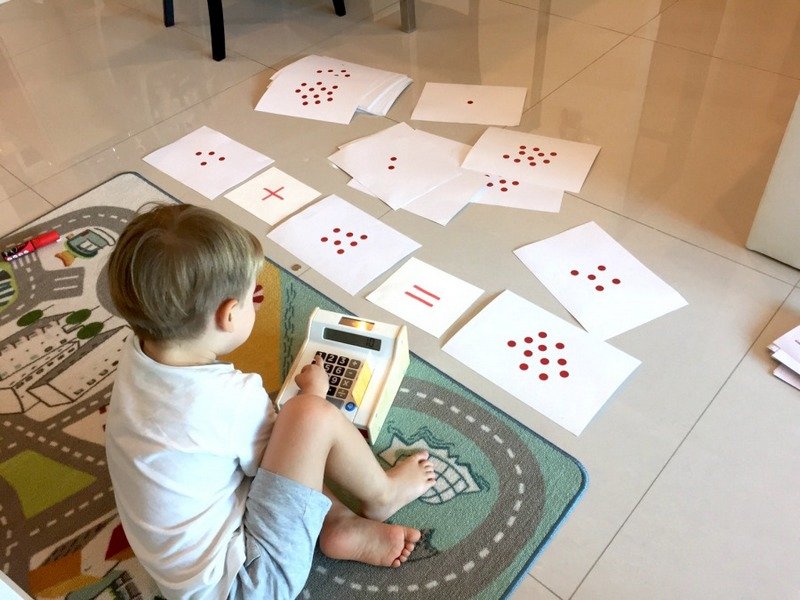 Мальчик сидит на полу, возле него карточки Домана для обучения счёту